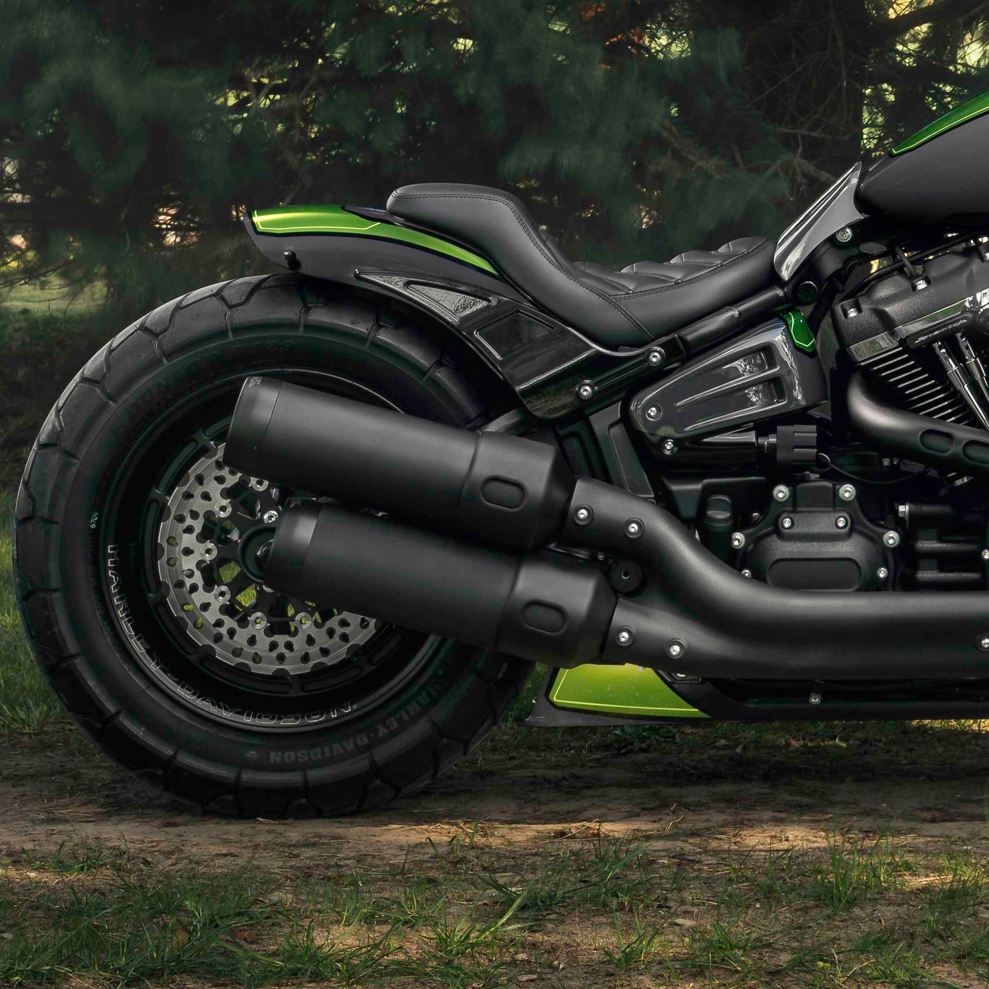 Zoomed  Harley Davidson Fat Bob motorcycle with Killer Custom parts from the side with some trees in the background