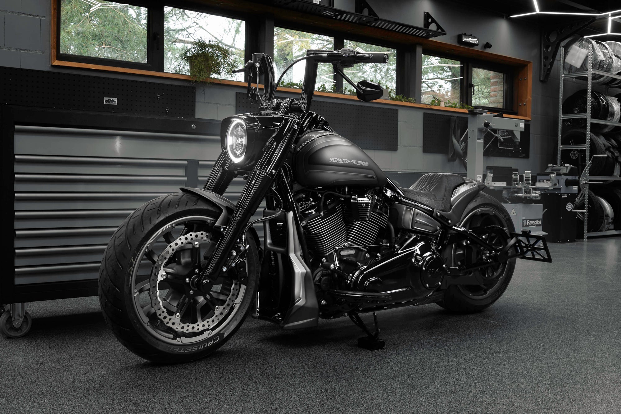 Modified Harley Davidson Fat Boy motorcycle with Killer Custom parts from the side in a modern bike shop with some windows in the background