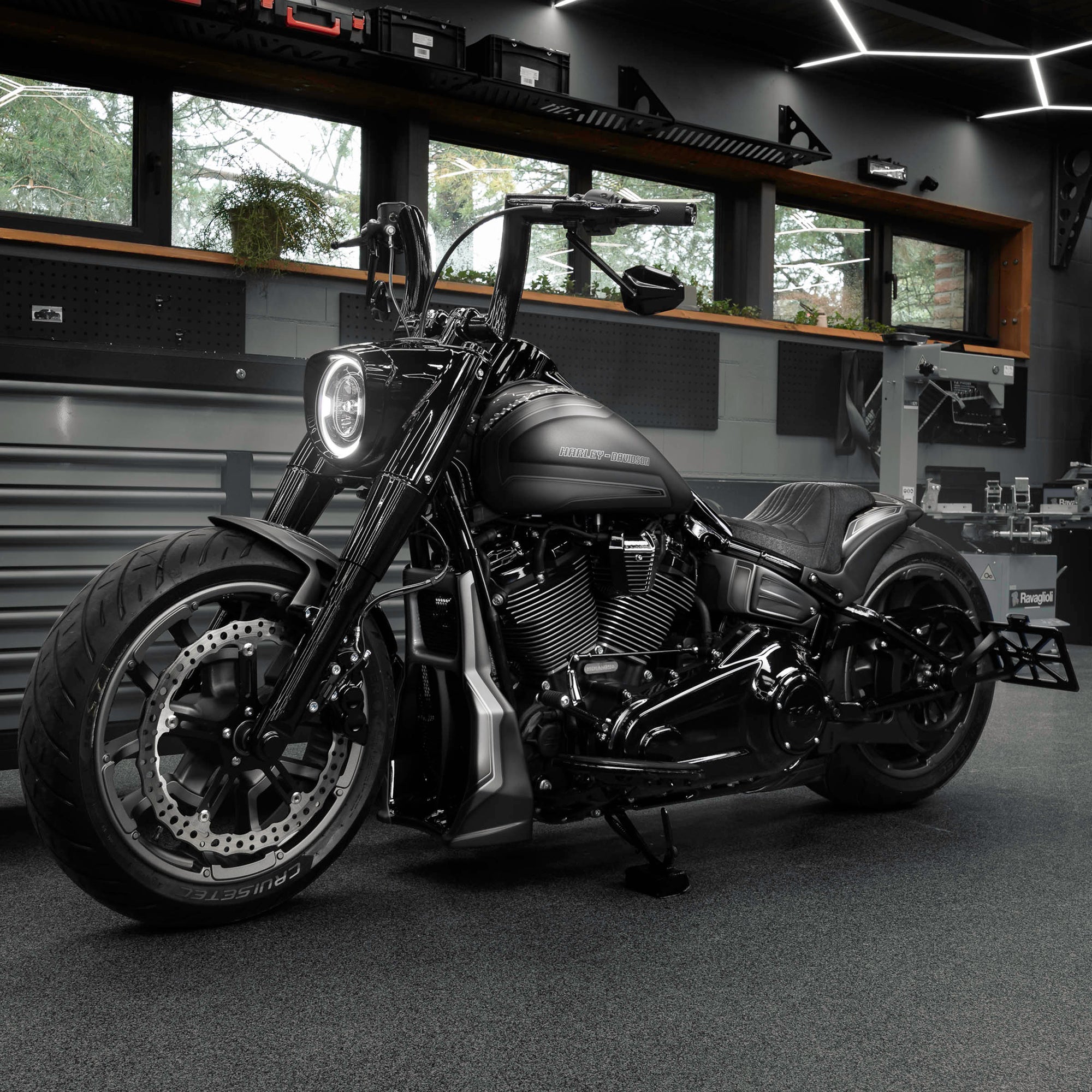 Modified Harley Davidson Fat Boy motorcycle with Killer Custom parts from the side in a modern bike shop with some windows in the background