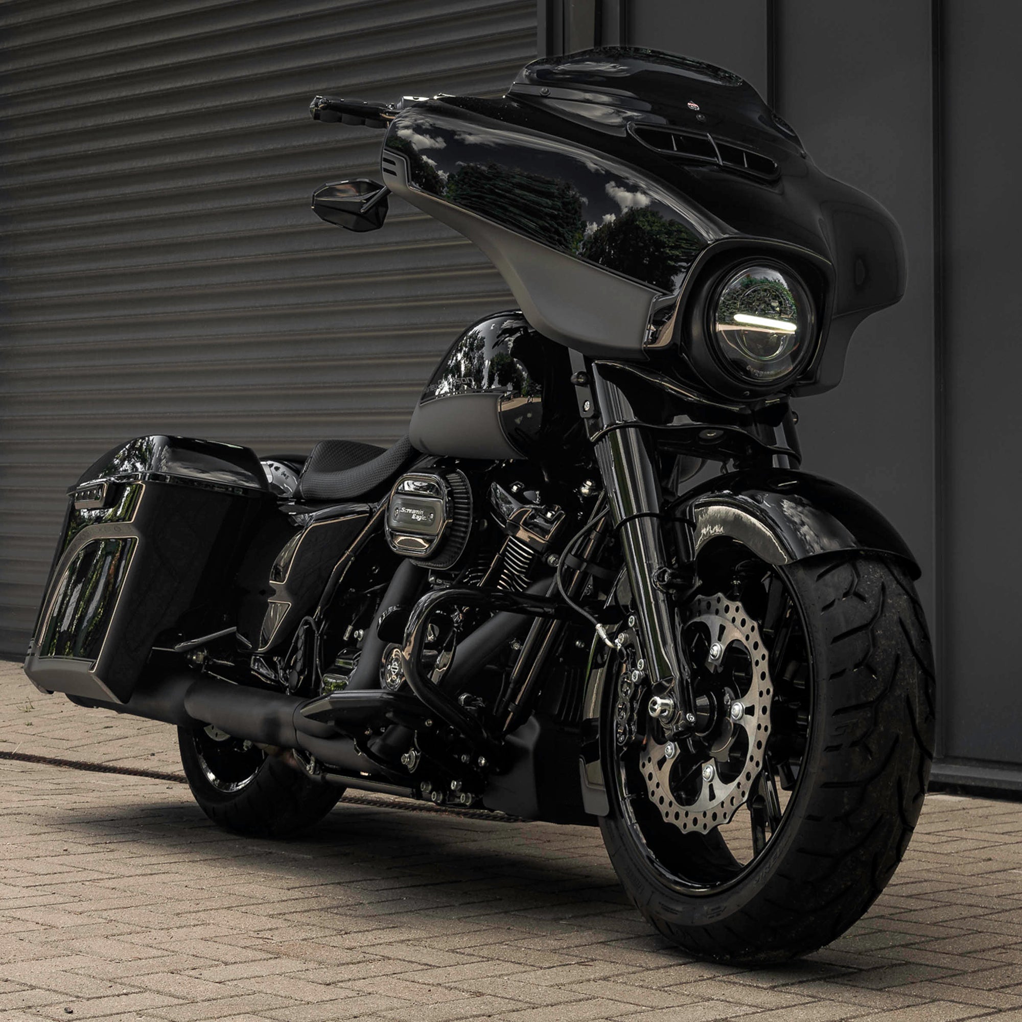 Modified Harley Davidson Street Glide motorcycle with Killer Custom parts from the front with a grey industrial wall in the background