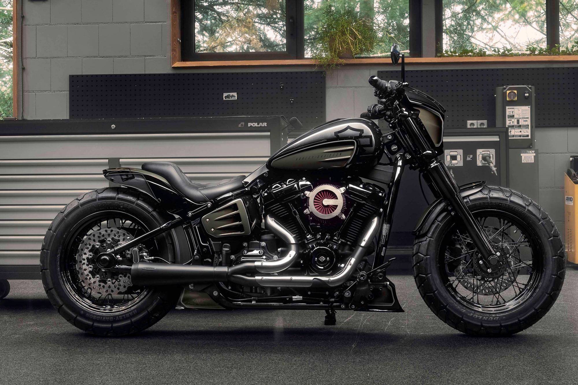 Modified Harley Davidson Street Bob motorcycle with Killer Custom parts from the side in a modern garage