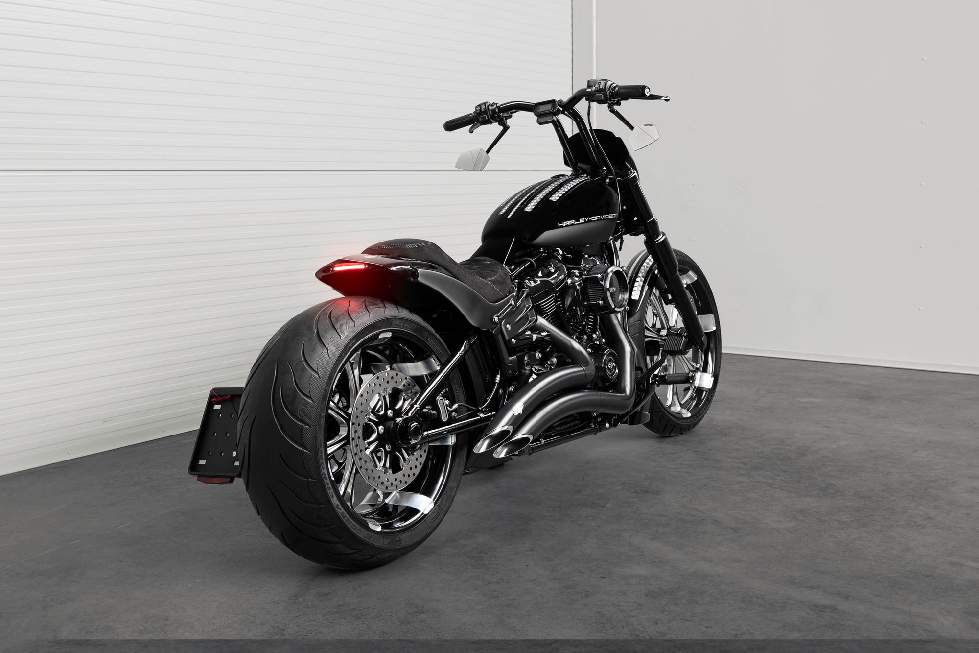 Harley Davidson motorcycle with Killer Custom parts from the rear in a white modern bike shop