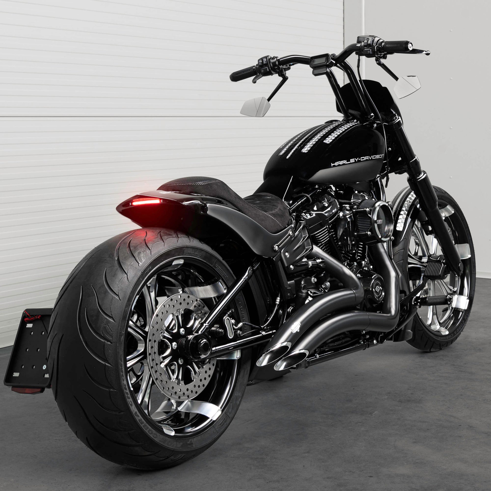 Harley Davidson motorcycle with Killer Custom parts from the rear in a white modern bike shop