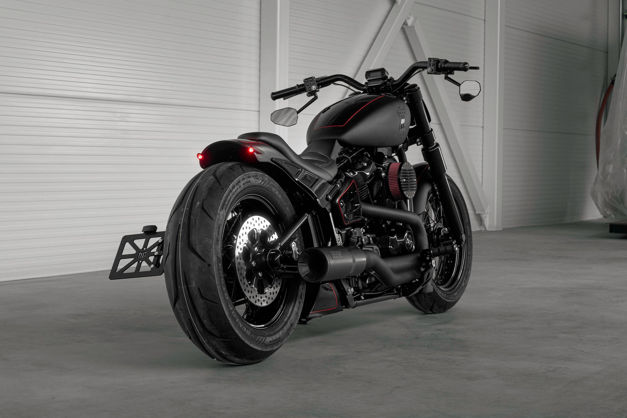 Harley Davidson motorcycle with Killer Custom parts from the rear in a modern white garage