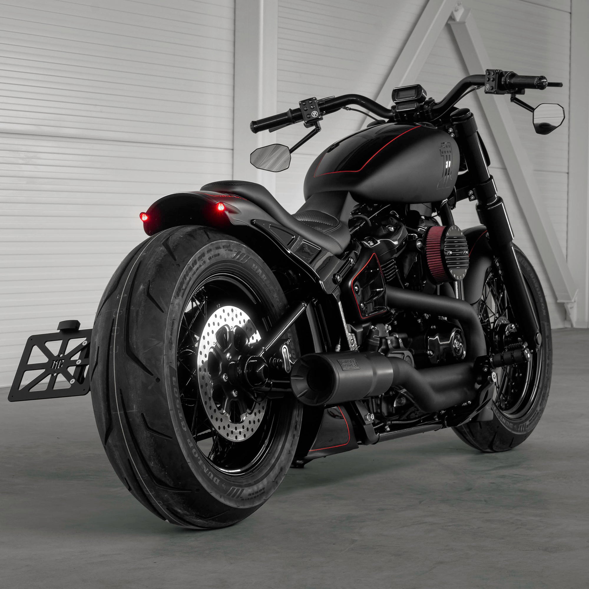 Harley Davidson motorcycle with Killer Custom parts from the rear in a modern white garage