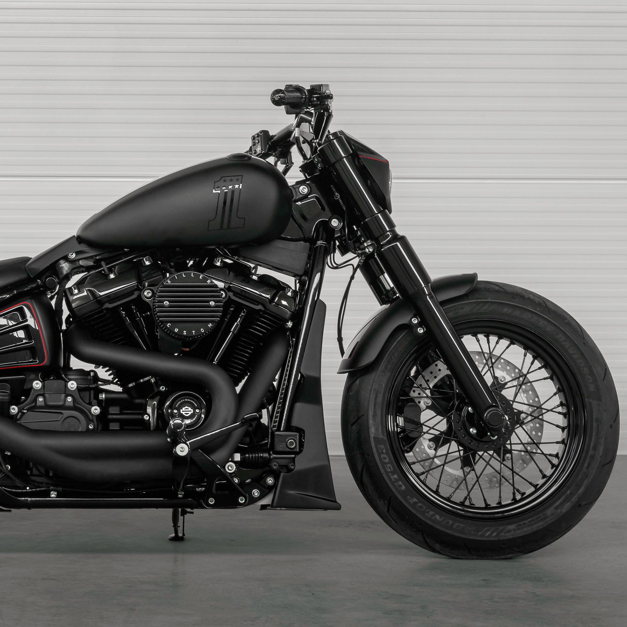 Zoomed Harley Davidson motorcycle with Killer Custom parts from the side with a white garage wall in the background