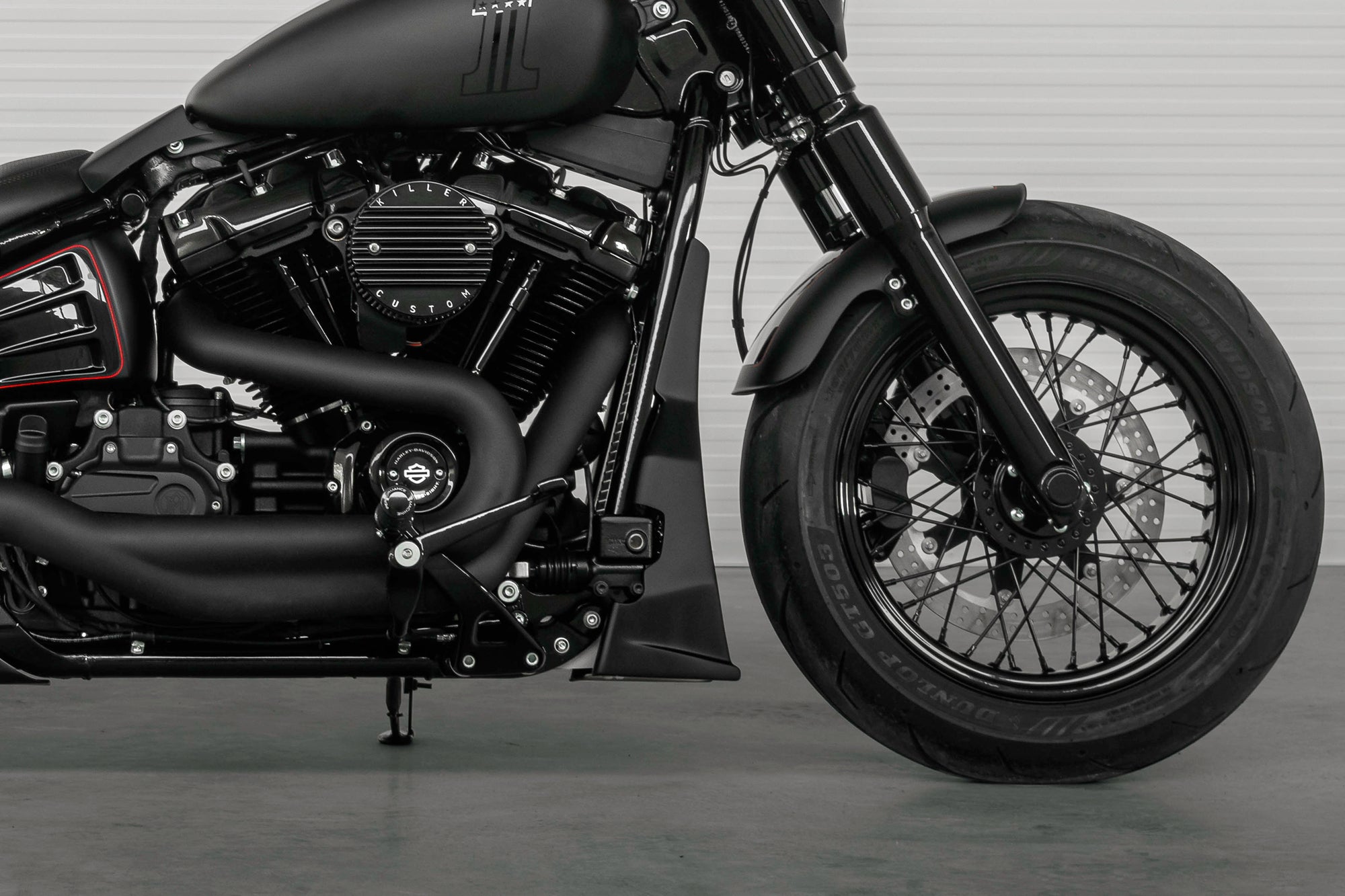 Zoomed Harley Davidson motorcycle with Killer Custom parts from the side in a modern white garage