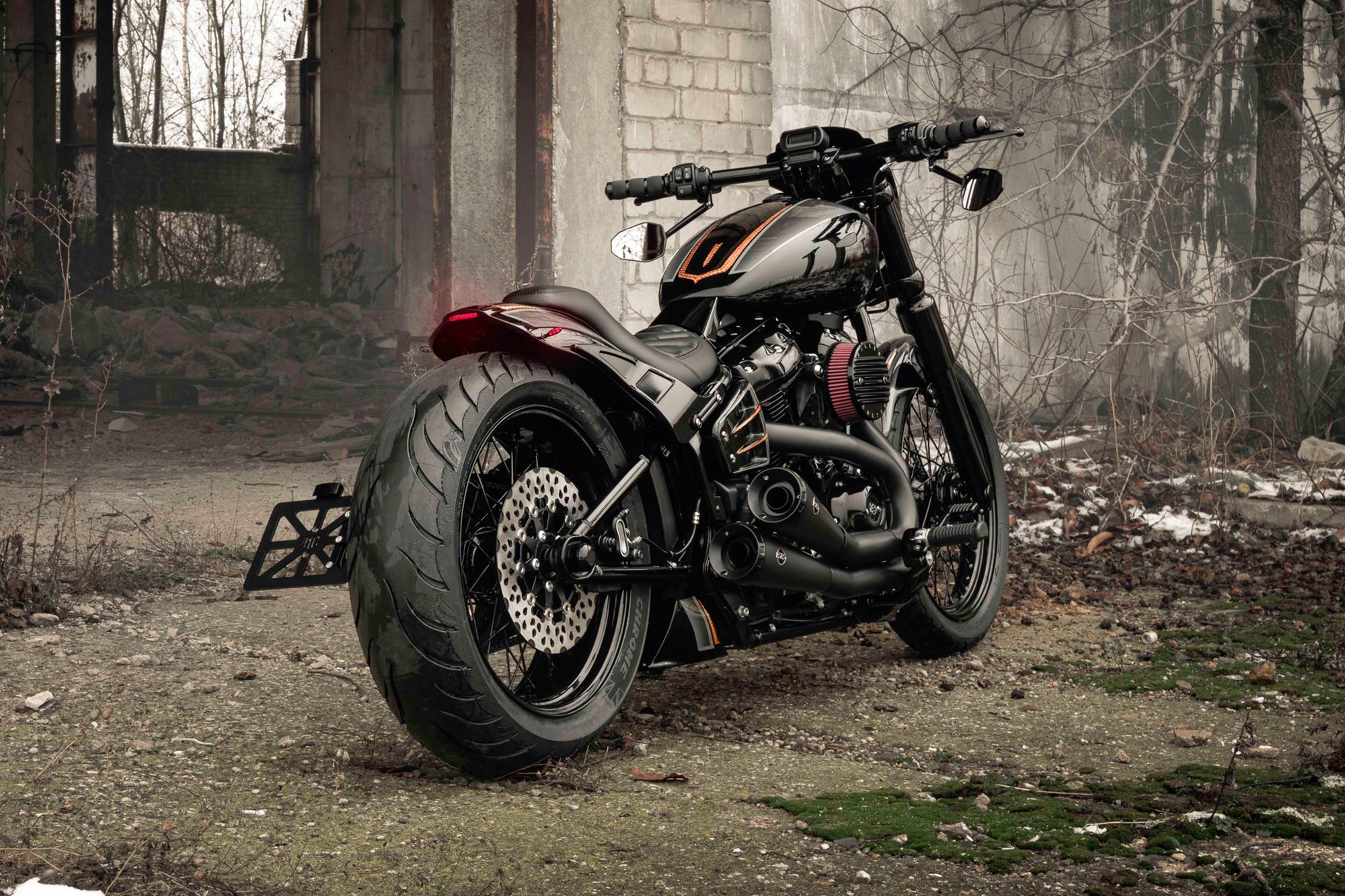Harley Davidson motorcycle with Killer Custom parts from the rear outside in an abandoned environment