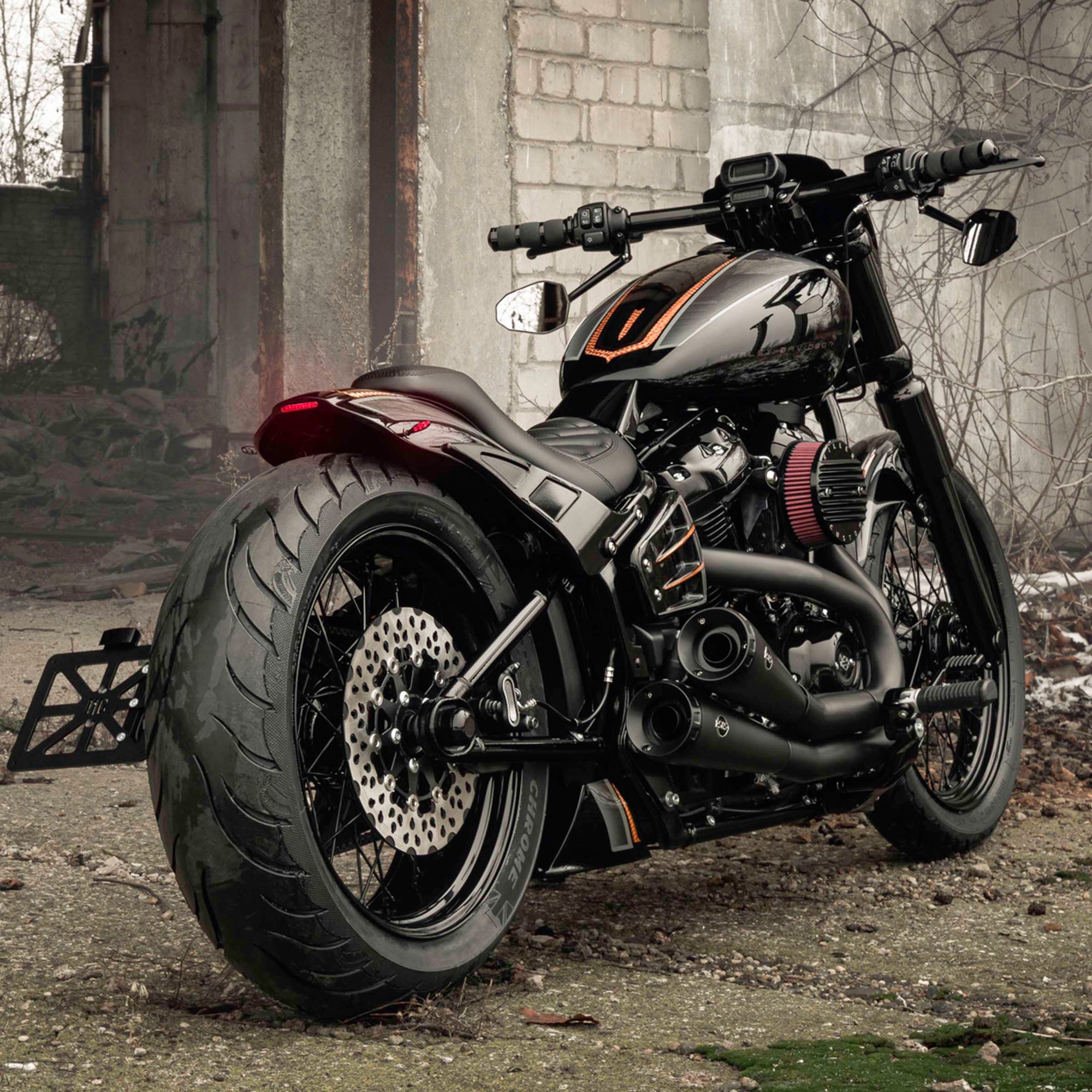 Modified Harley Davidson Street Bob motorcycle with Killer Custom parts from the rear outside in an abandoned environment