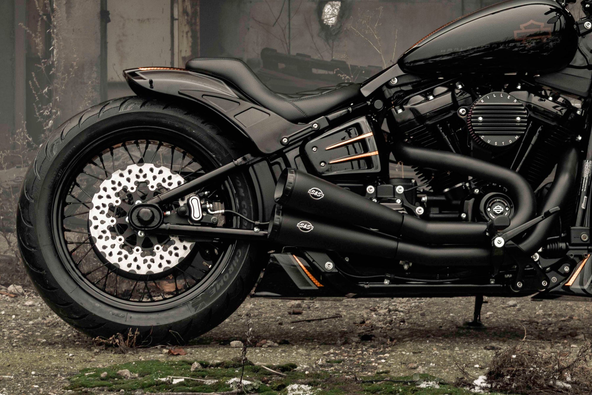 Zoomed Harley Davidson motorcycle with Killer Custom parts from the side outside in an abandoned environment