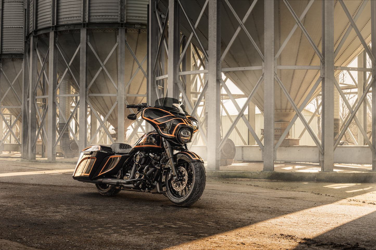 Harley Davidson motorcycle with Killer Custom extended gas tank and side cover touring kit from the side, outside on a sunny day in an industrial environment