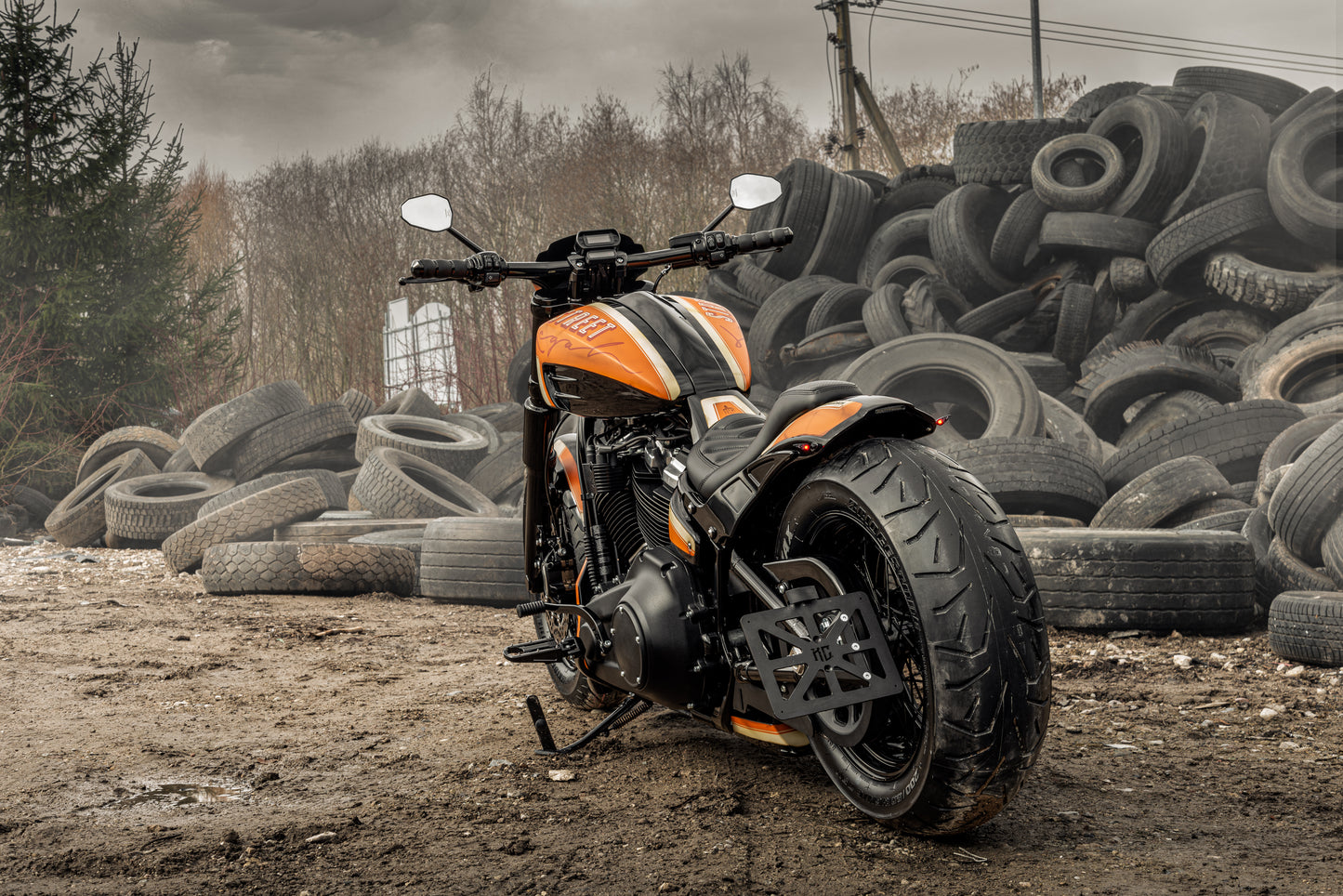 Harley Davidson motorcycle with Killer Custom gas tank cover and console kit from the rear outside with a pile of tires in the background