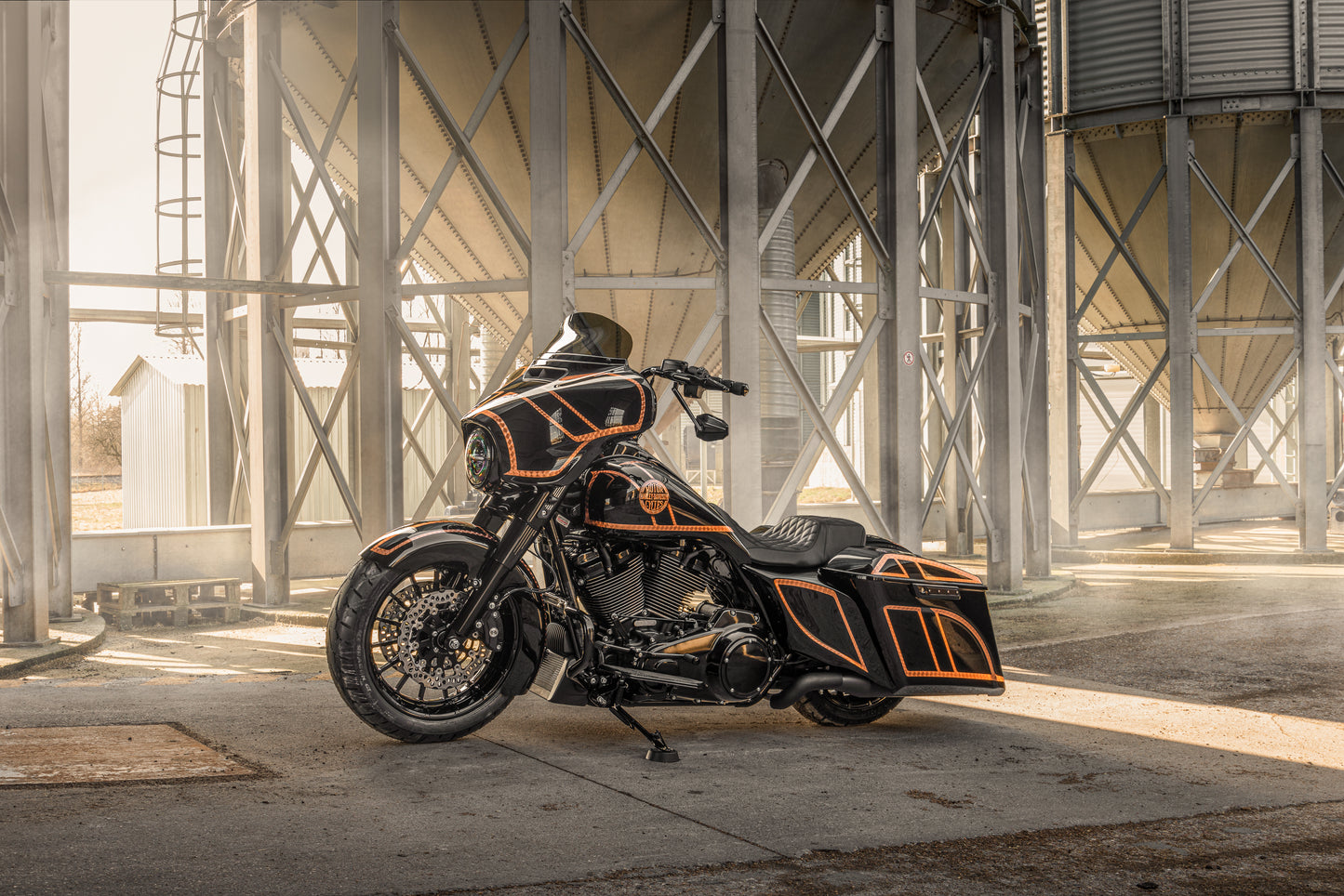 Harley Davidson motorcycle with Killer Custom extended gas tank and side cover touring kit from the side, outside on a sunny day in an industrial environment