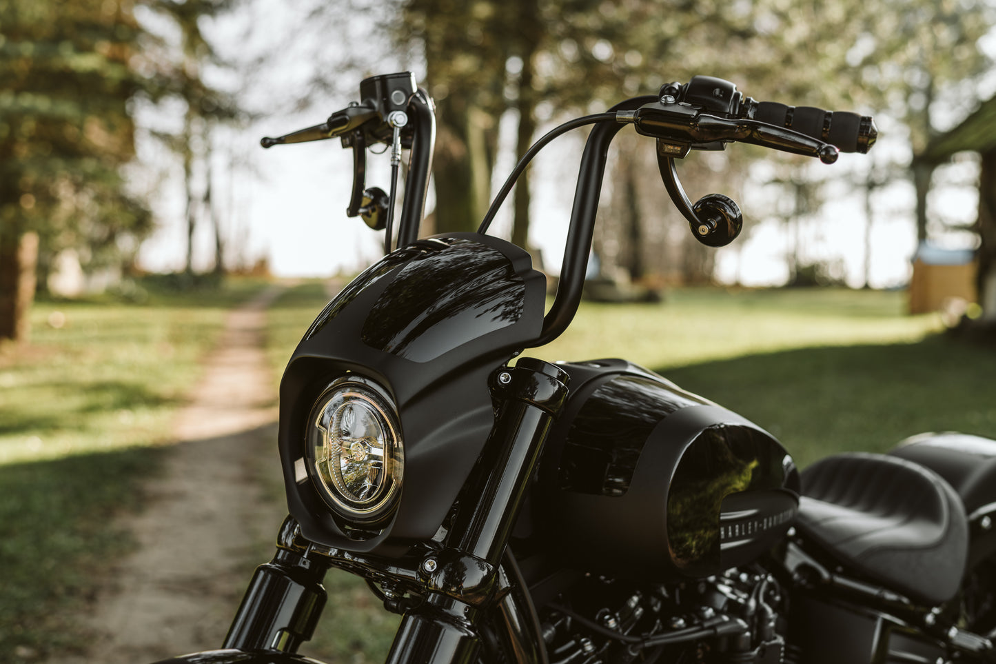 Zoomed Harley Davidson motorcycle with Killer Custom "Aggressor" headlight fairing from the front outside on a sunny day in the forest
