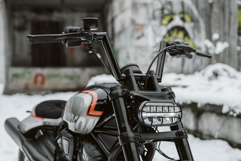 Harley Davidson motorcycle with Killer Custom hydraulic brake and clutch hoses extension from the front with visible snow and graffiti in the background