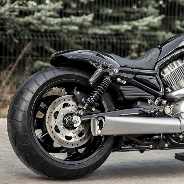 Zoomed Harley Davidson motorcycle with Killer Custom V-Rod nitrogen rear shocks with some blurred trees in the background