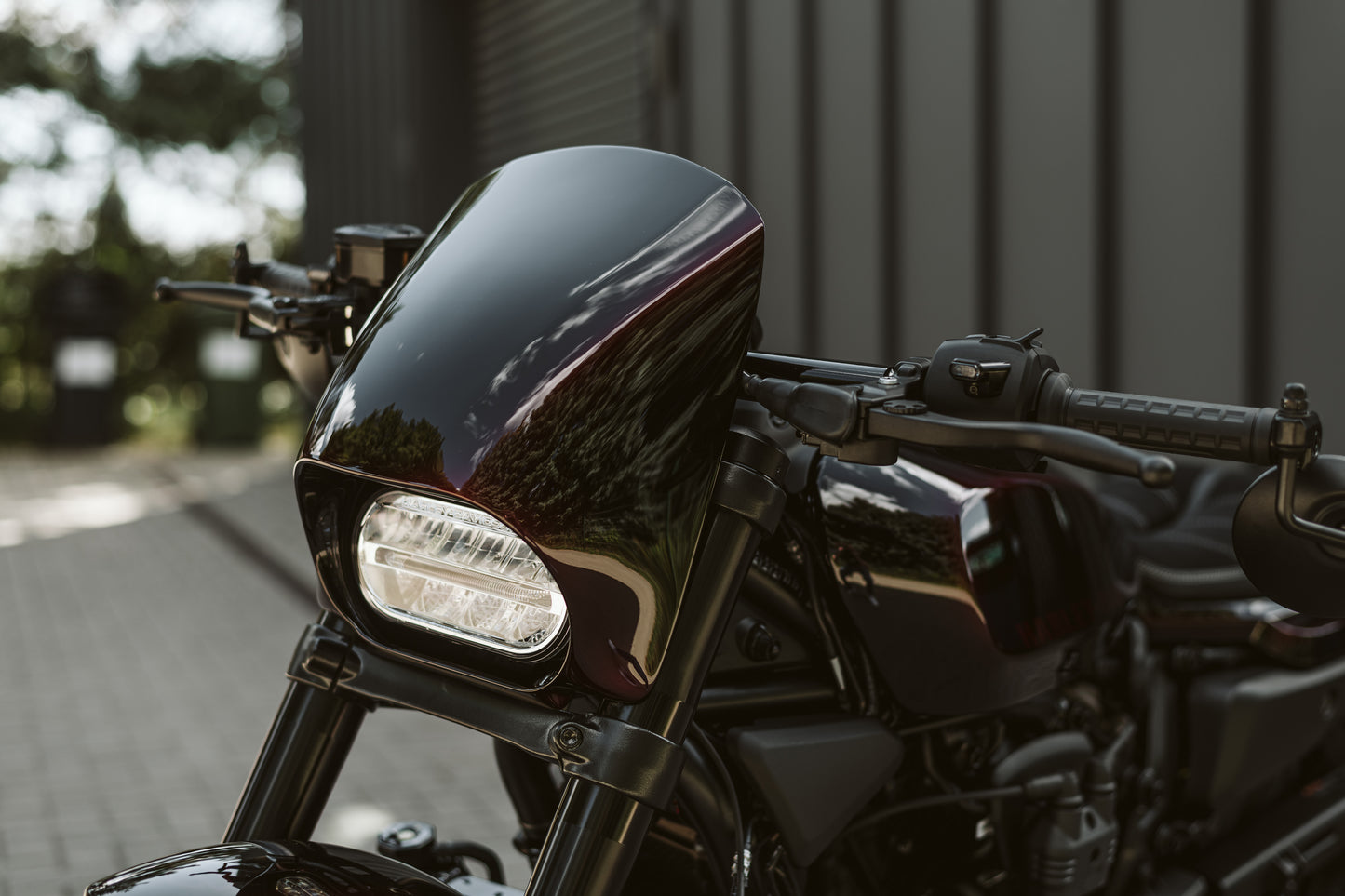 Harley Davidson motorcycle with Killer Custom Harley Davidson "Road Warrior" headlight fairing mask outside in front of a garage