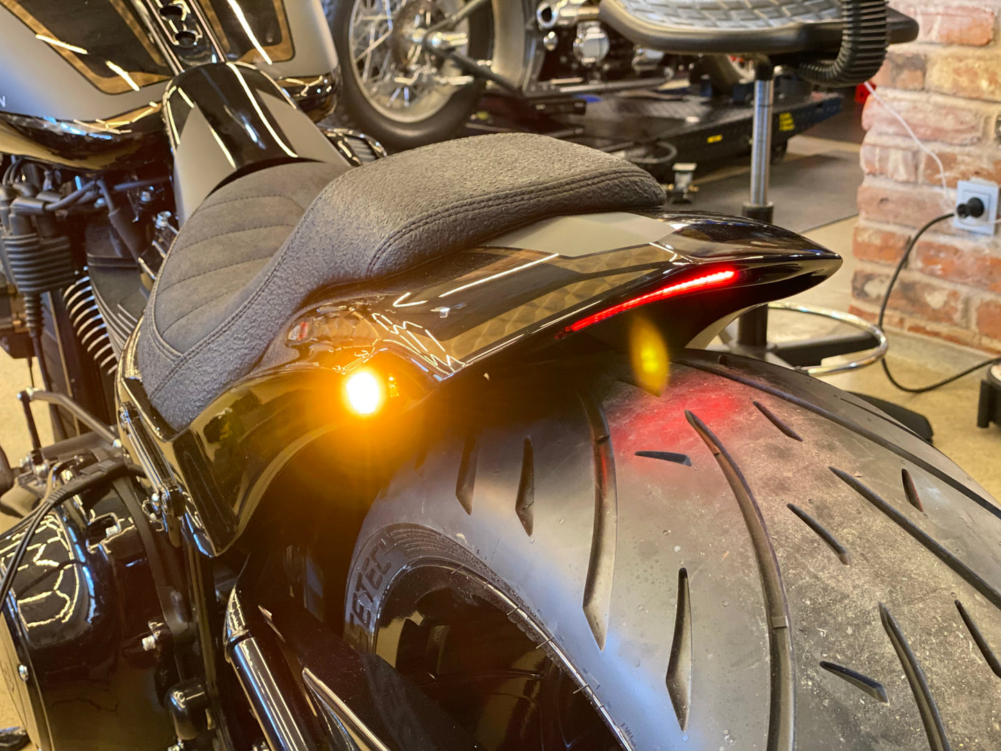 Zoomed Harley Davidson motorcycle with Killer Custom "Avenger" rear fender kit from the rear in a bike shop
