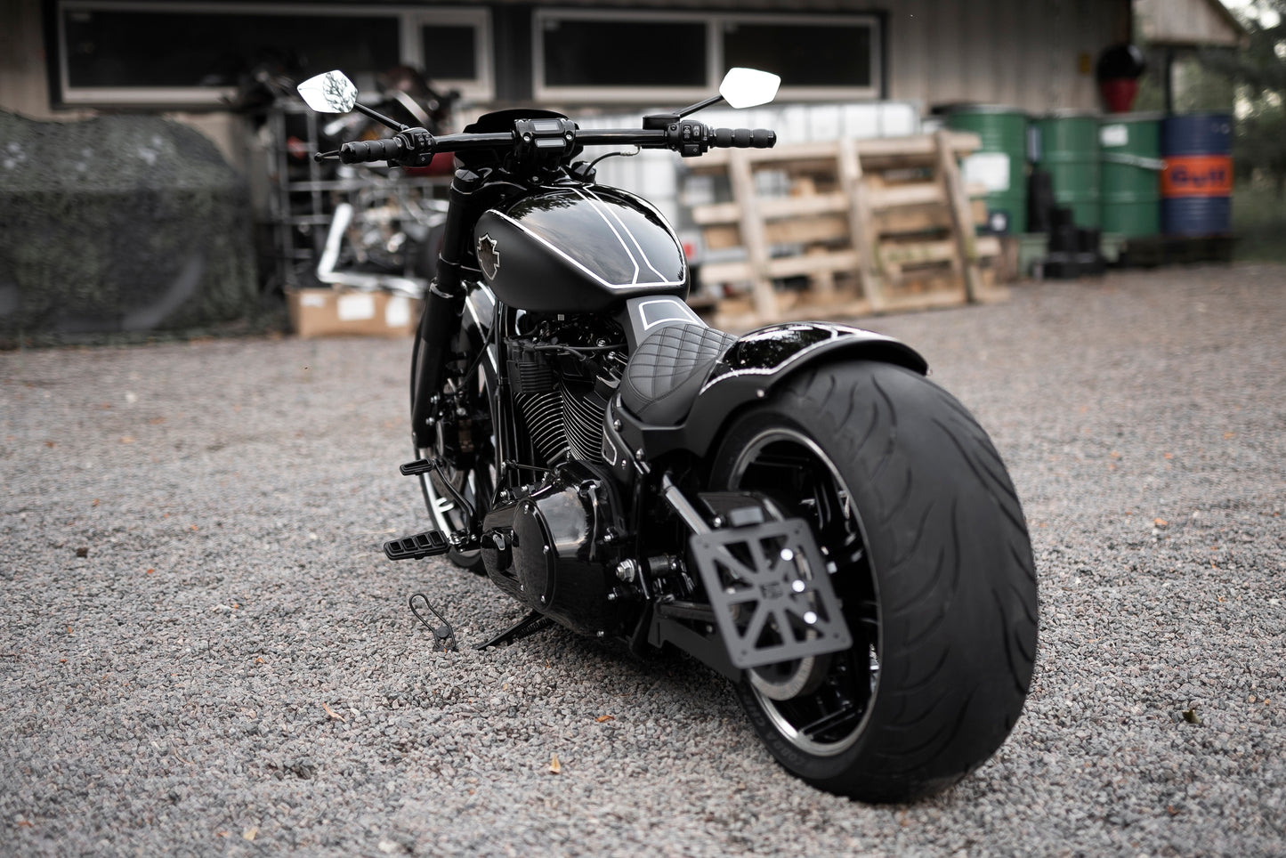 Harley Davidson motorcycle with Killer Custom license plate bracket from the rear outside with some industrial equipment in the background