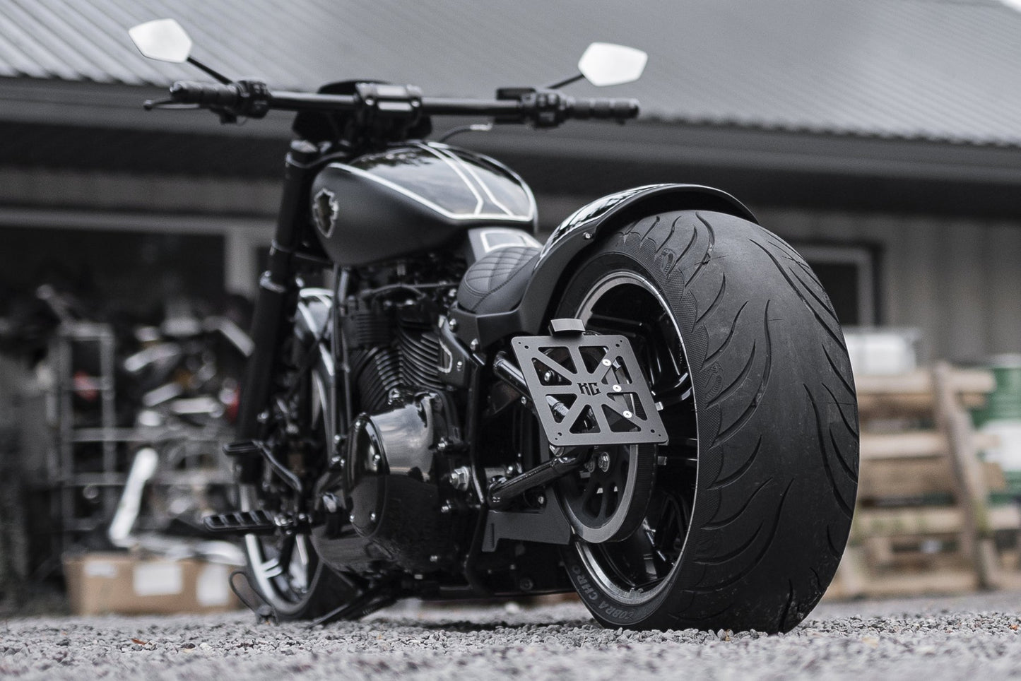 Harley Davidson motorcycle with Killer Custom license plate bracket outside with industrial equipment in the background