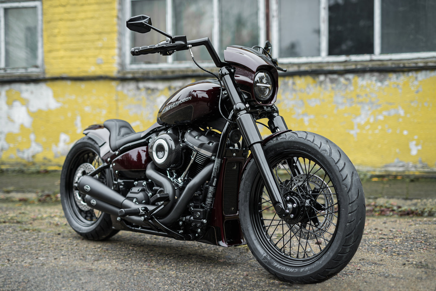 Harley Davidson motorcycle with Killer Custom Headlight ECE approved with parking light from the side with a yellow aged house in the background
