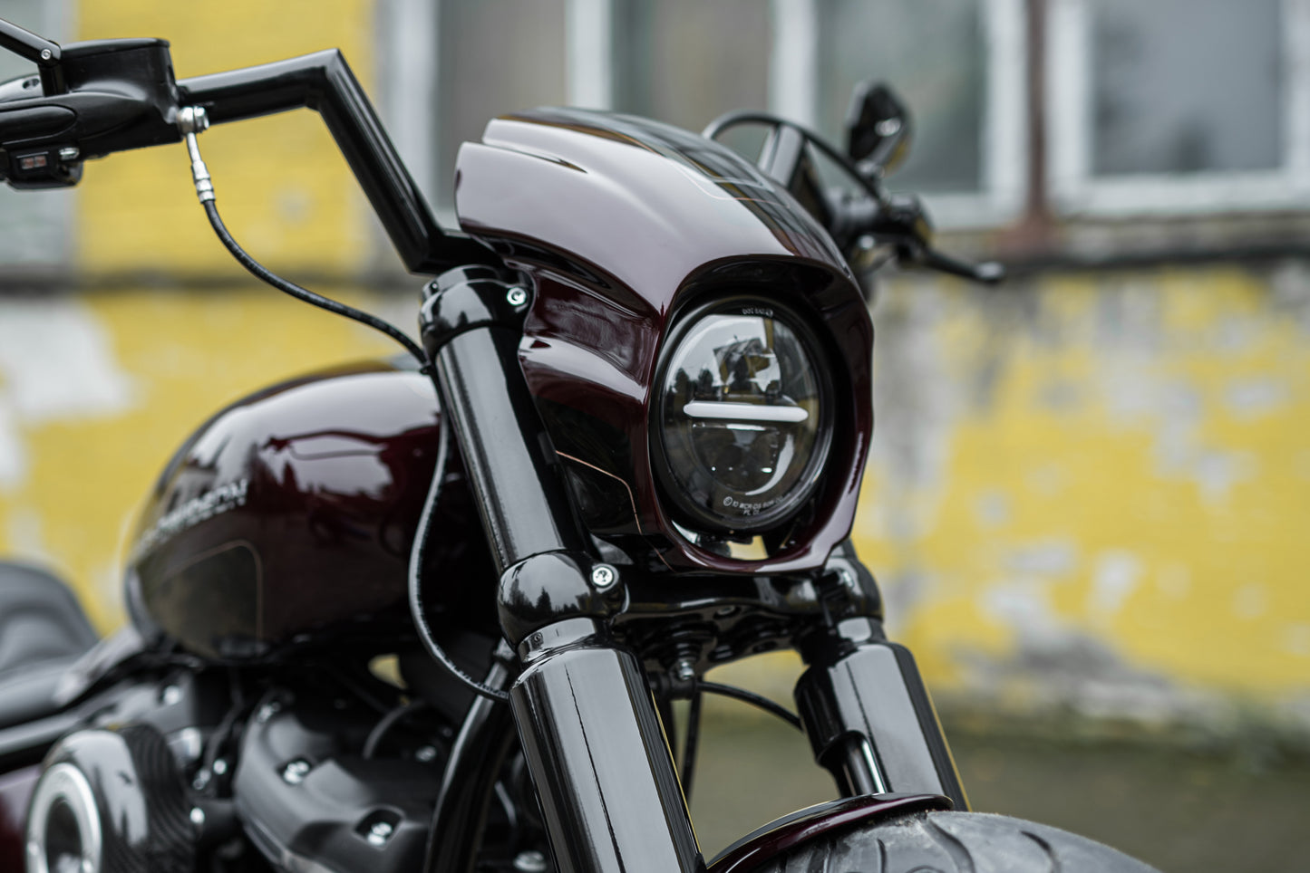 Zoomed Harley Davidson motorcycle with Killer Custom Headlight ECE approved with parking light from the front with a blurry aged wall in the background