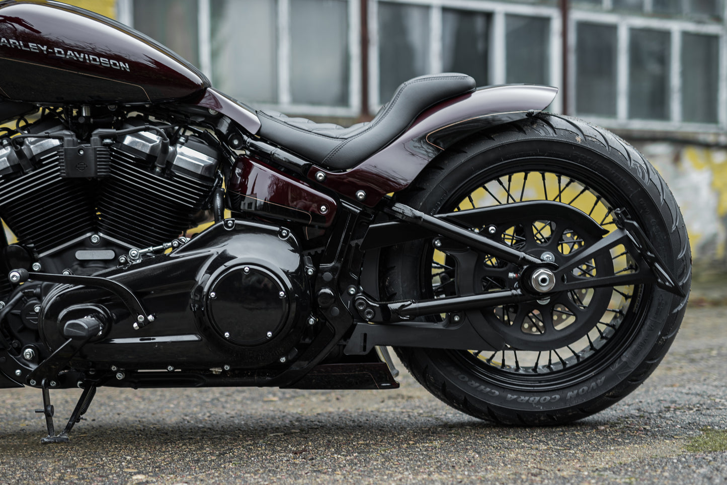 Zoomed Harley Davidson motorcycle with Killer Custom "Bobbstr" rear fender from the rear near an abandoned building