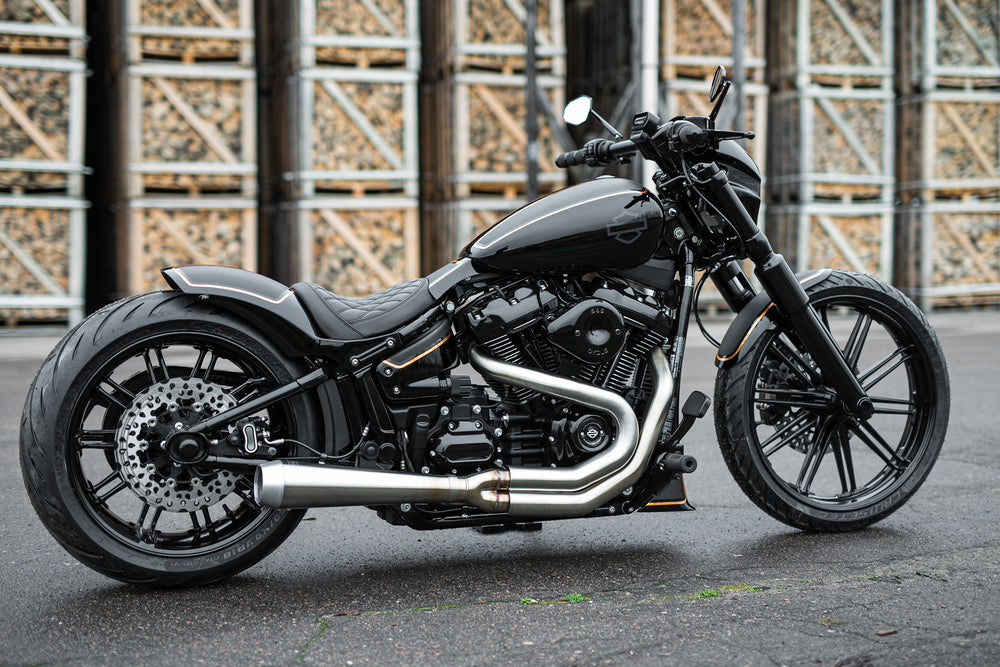 Harley Davidson motorcycle with Killer Custom rear axle cover set from the side in an industrial environment