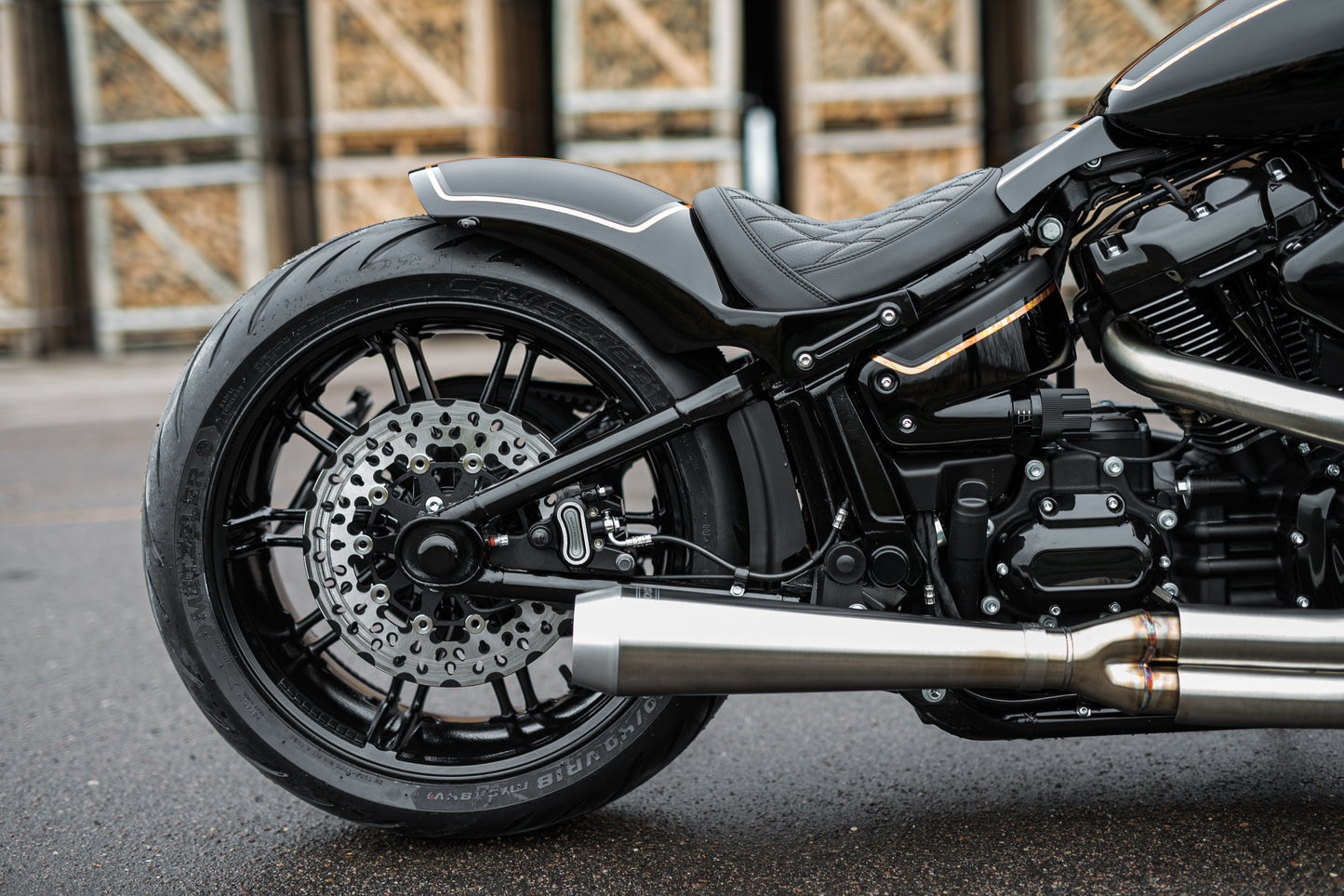 Harley Davidson motorcycle with Killer Custom swingarm axle cover set from the side in an industrial environment