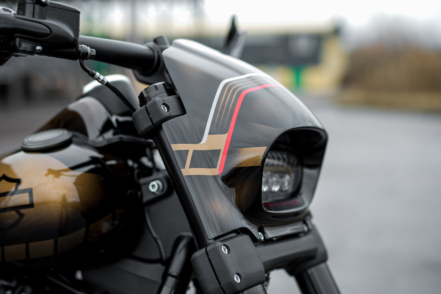 Zoomed Harley Davidson motorcycle with Killer Custom fat bob headlight fairing from the side blurry background
