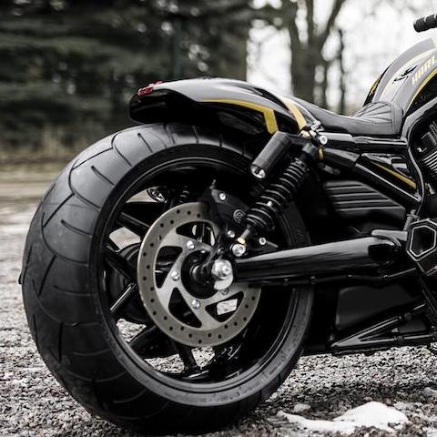 Zoomed Harley Davidson motorcycle with Killer Custom V-Rod nitrogen rear shocks with visible snow and trees in the background