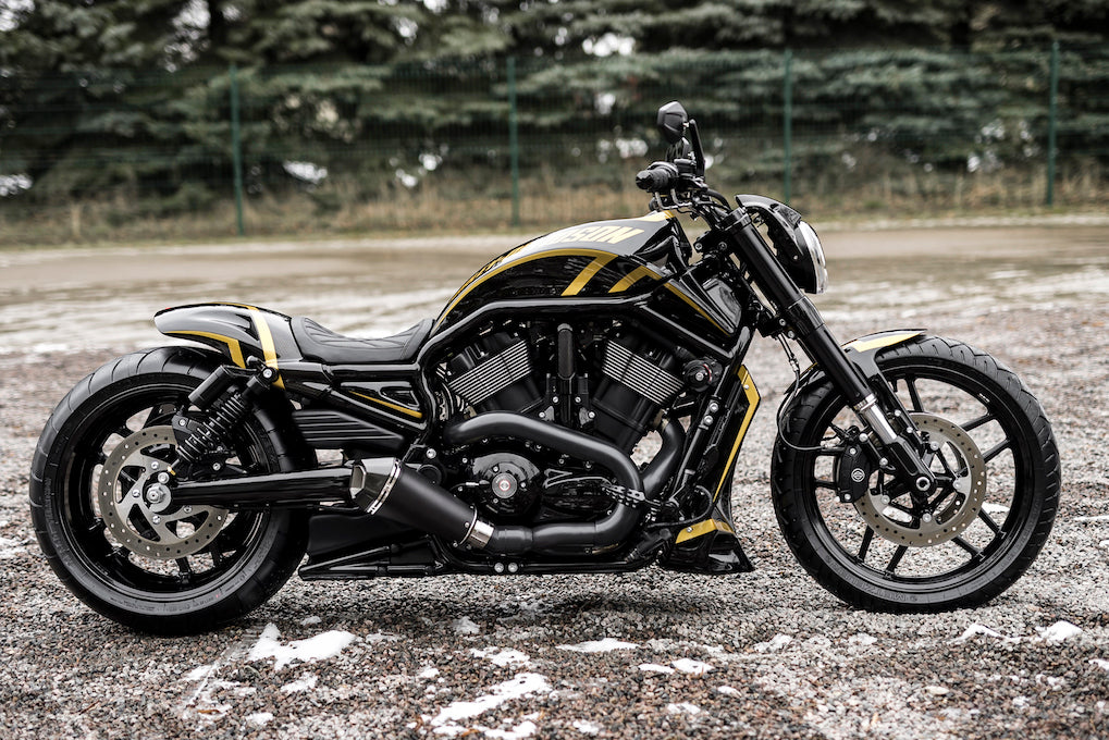 Harley Davidson motorcycle with Killer Custom V-Rod seat for "Short/Smooth Oval" rear fenders from the side, outside on a gloomy day with some trees and visible snow in the background