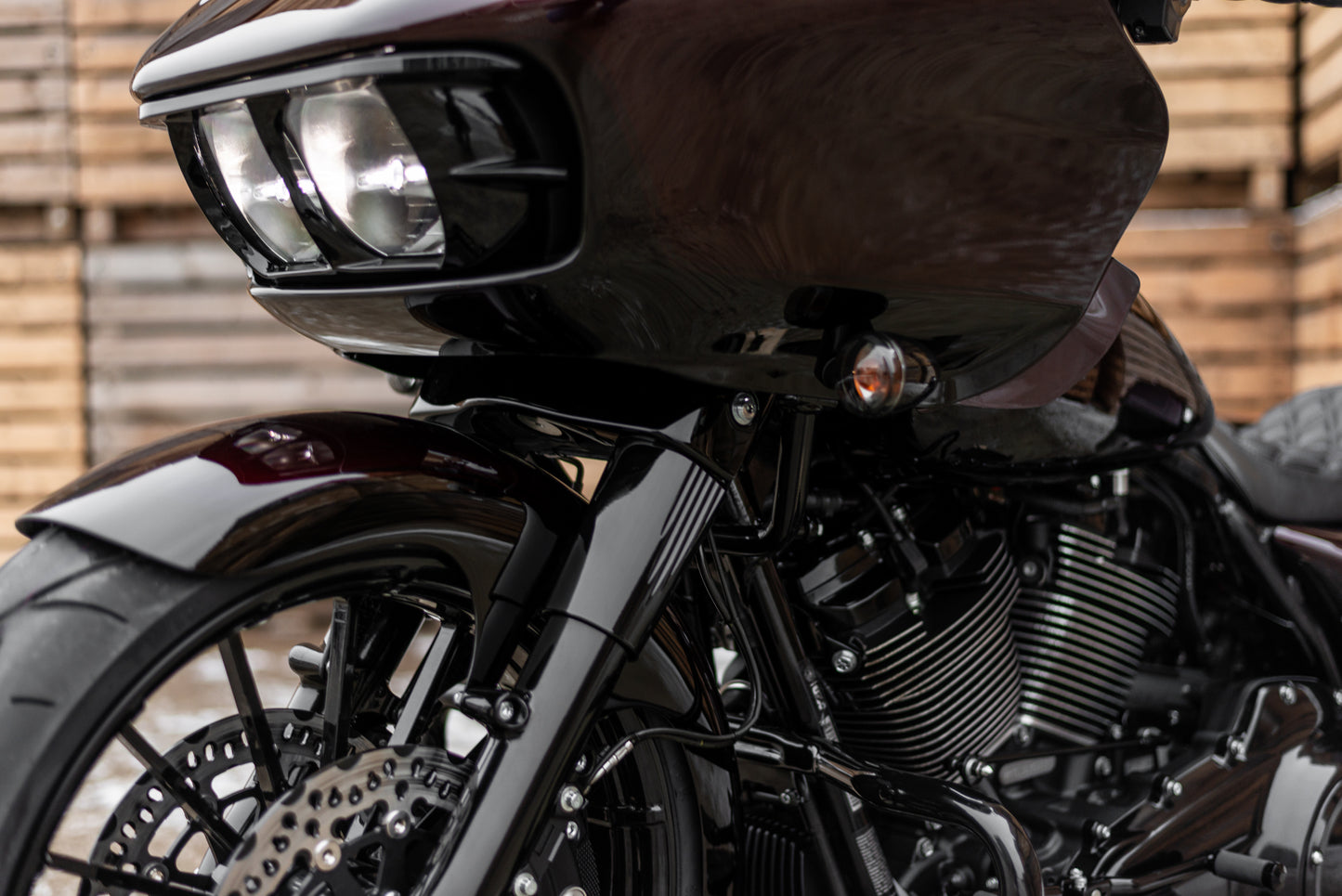 Zoomed Harley Davidson motorcycle with Killer Custom upper fork covers from the side with a wooden wall in the background