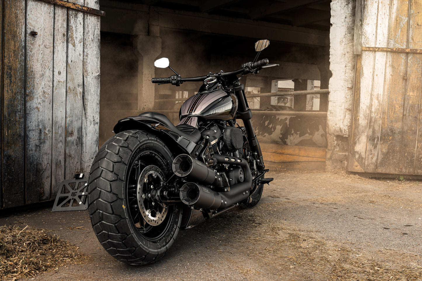 Harley Davidson motorcycle with back frame spoiler from the rear next to the farm building