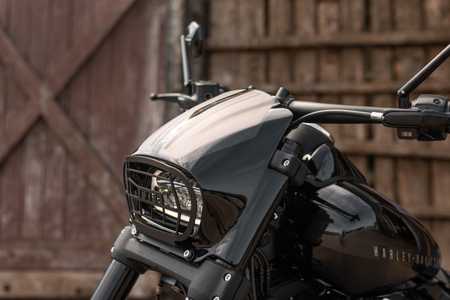 Zoomed Harley Davidson motorcycle with Killer Custom fat bob headlight fairing from the front next to the wooden door