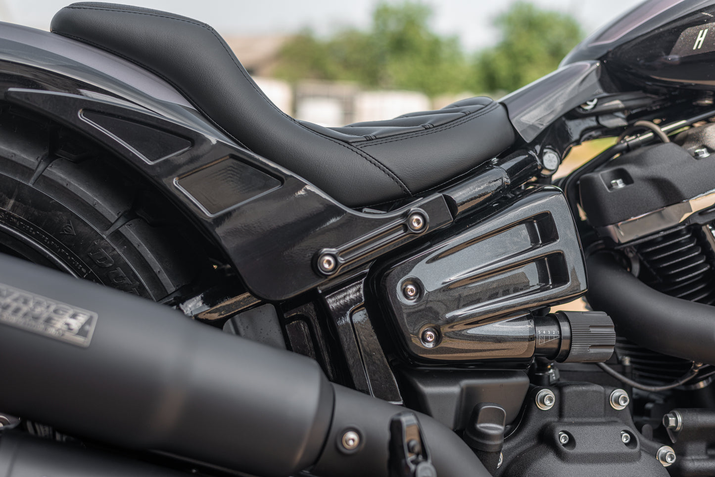 Zoomed Harley Davidson motorcycle with "Avenger" side covers from the side green blurry background