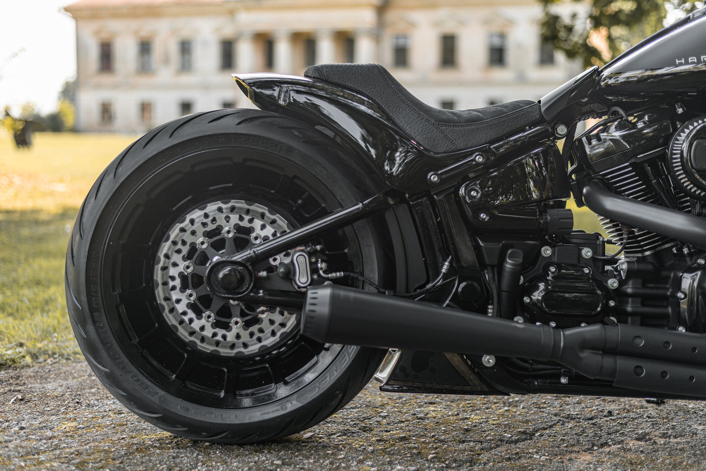 Harley Davidson motorcycle with Killer Custom "Avenger" rear fender kit from the side with an old mansion in the background