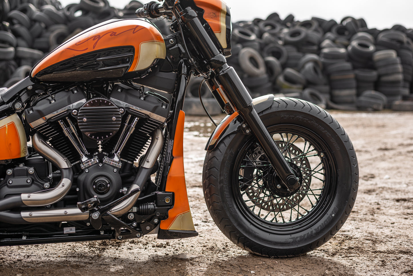 Harley Davidson motorcycle with Killer Custom gas tank cover and console kit from the side with a pile of tires in the background