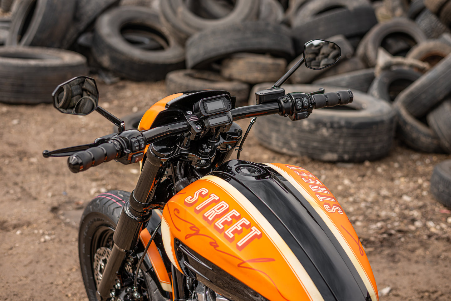 Zoomed Harley Davidson motorcycle with Killer Custom fork end caps outside with a pile of tires in the background
