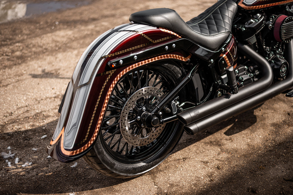 Zoomed Harley Davidson motorcycle with Killer Custom rear fender with tip from the side outside on a sunny day