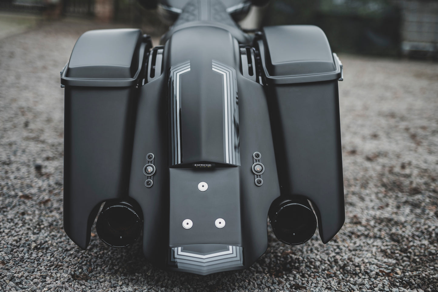 Zoomed Harley Davidson motorcycle with Killer Custom extended bagger saddlebags from the rear outside on a gloomy day blurry background