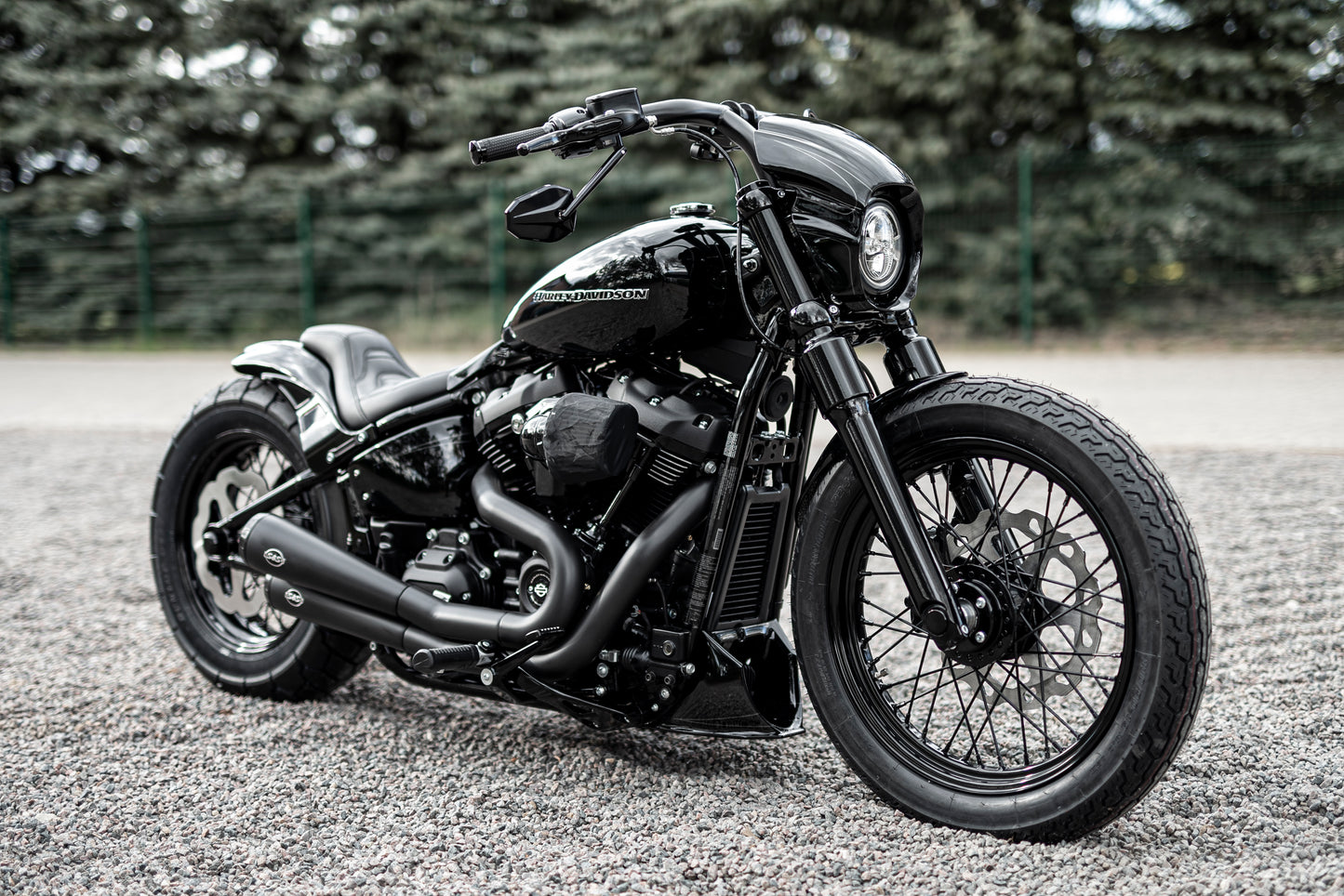 Harley Davidson motorcycle with Killer Custom front fork lowering kit from the side with some trees in the background
