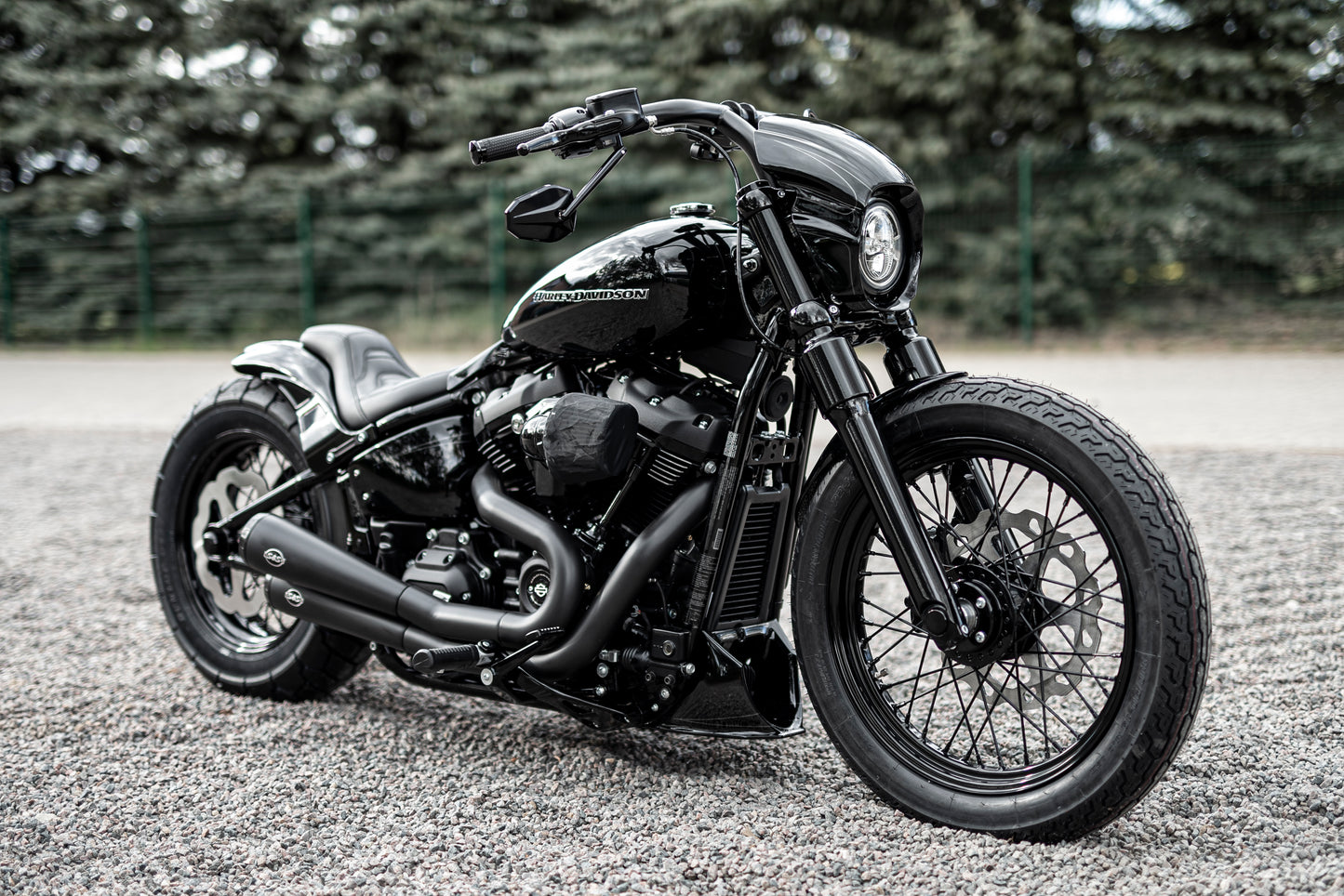 Harley Davidson motorcycle with Killer Custom booster mirrors from the side with a blurry nature background