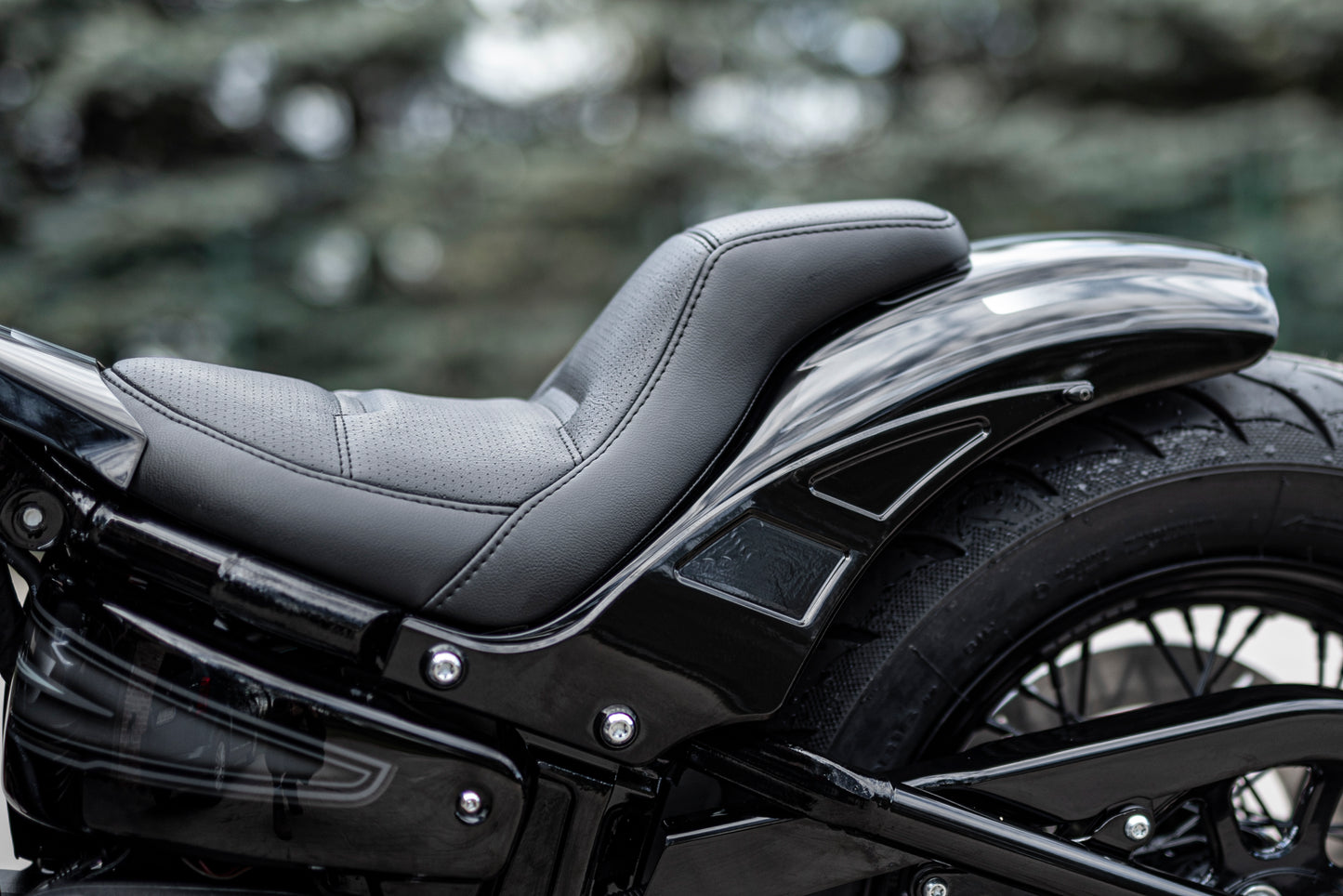 Zoomed Harley Davidson motorcycle with Killer Custom seat for rear fenders from the side blurry background