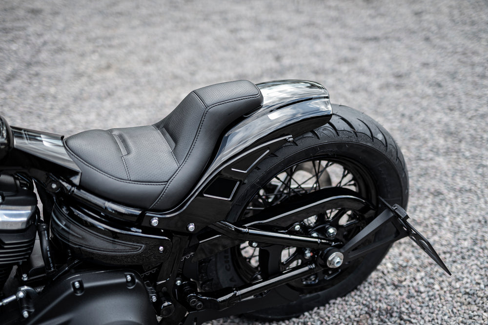 Zoomed Harley Davidson motorcycle with Killer Custom seat for rear fenders from the side blurry grey background