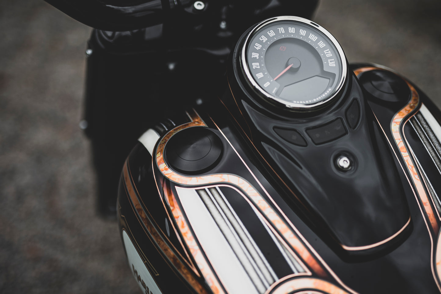 Zoomed Harley Davidson motorcycle with Killer Custom flush-mount fuel cap and left side tank cap kit from above blurry background