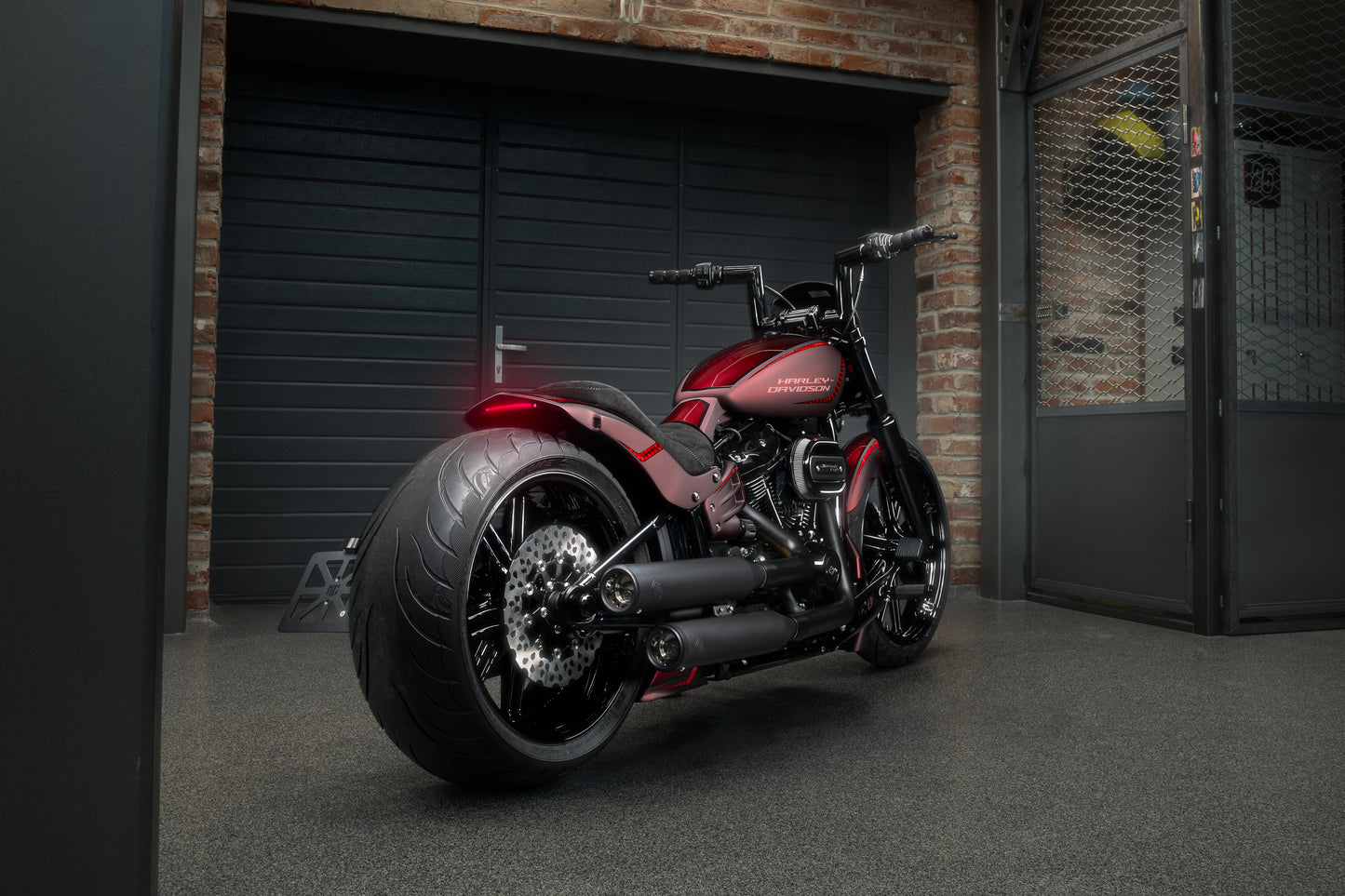 Harley Davidson motorcycle with Killer Custom "Killer Bull' fat handlebars from the rear in an industrial environment