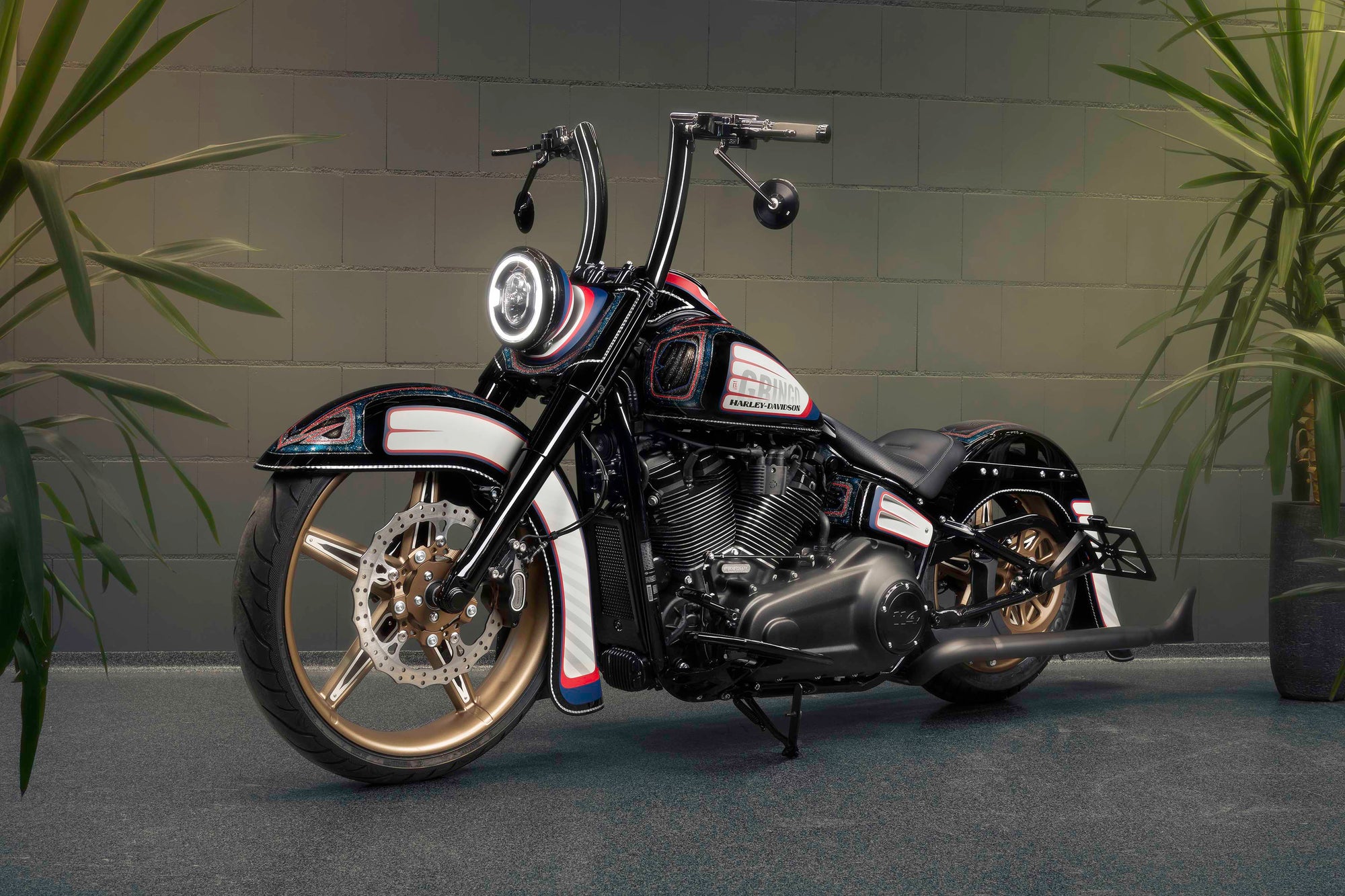 Modified Harley Davidson motorcycle with Killer Custom parts from the side grey brick wall in the background